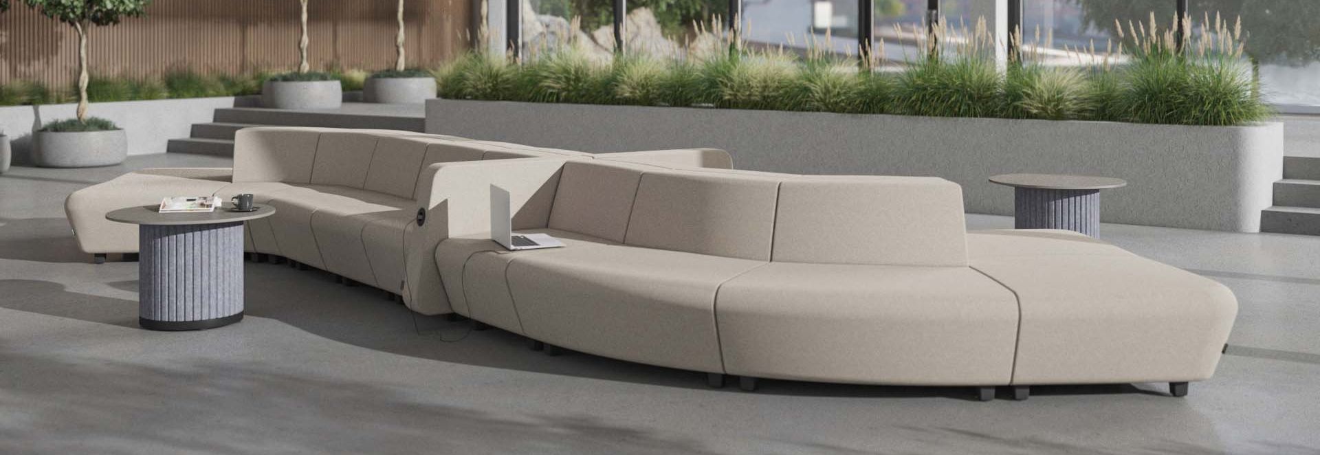 Modulaire beige lounge bank met een modern, zacht ontwerp, perfect voor een ontspanningsruimte in een kantooromgeving, voorzien van geïntegreerde stopcontacten en tafelbladen